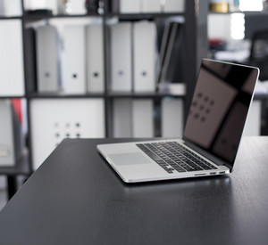 Ein Laptop steht auf einem Tisch vor einem Aktenschrank