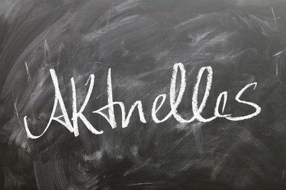 Kreidetafel mit dem groß in weißer Kreide geschriebenen Wort „Aktuelles“.