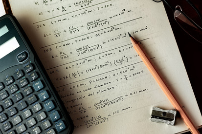 Heft mit mathematischen Inhalten, Taschenrechner und Bleistift