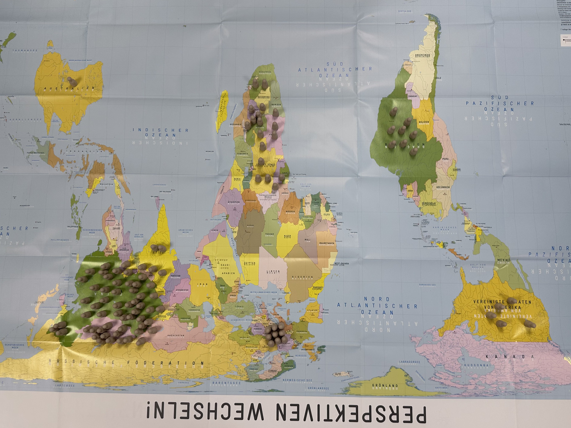 Eine auf dem Kopf stehende Weltkarte als Spielplan des "Eine-Welt-Spiels" mit der Bildunterschrift "Perspektiven wechseln"