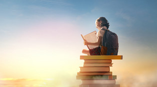 Kind sitzt auf vielen Büchern