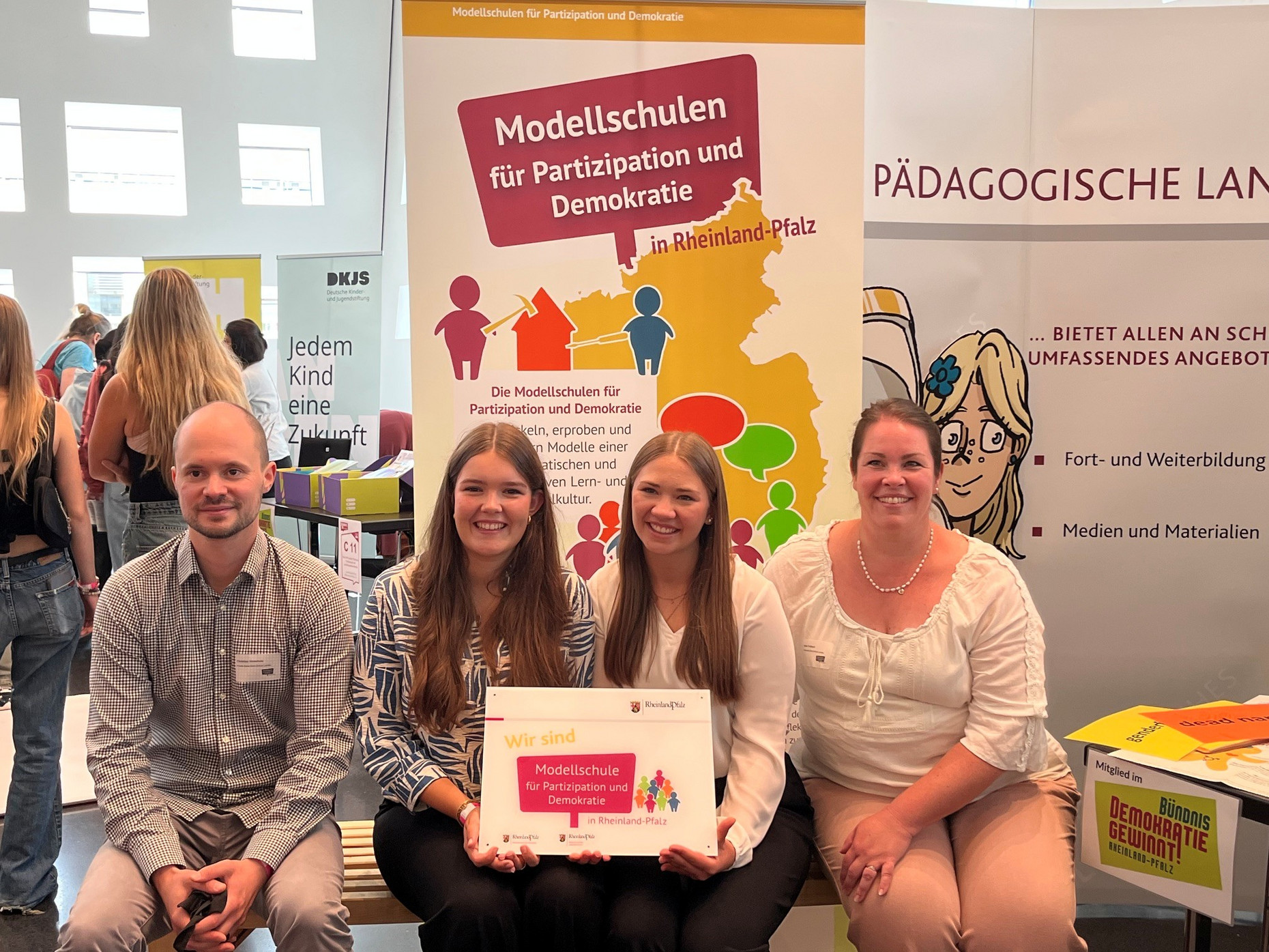 Schülerinnen und Lehrkräfte einer neuen Modellschule halten ihr neues Eingangsschild für die Schule hoch.