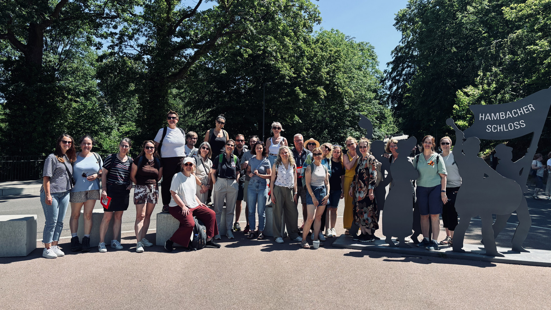 Das Kollegium des Studienseminars steht zum Gruppenfoto neben dem Schild des Hambacher Schlosses