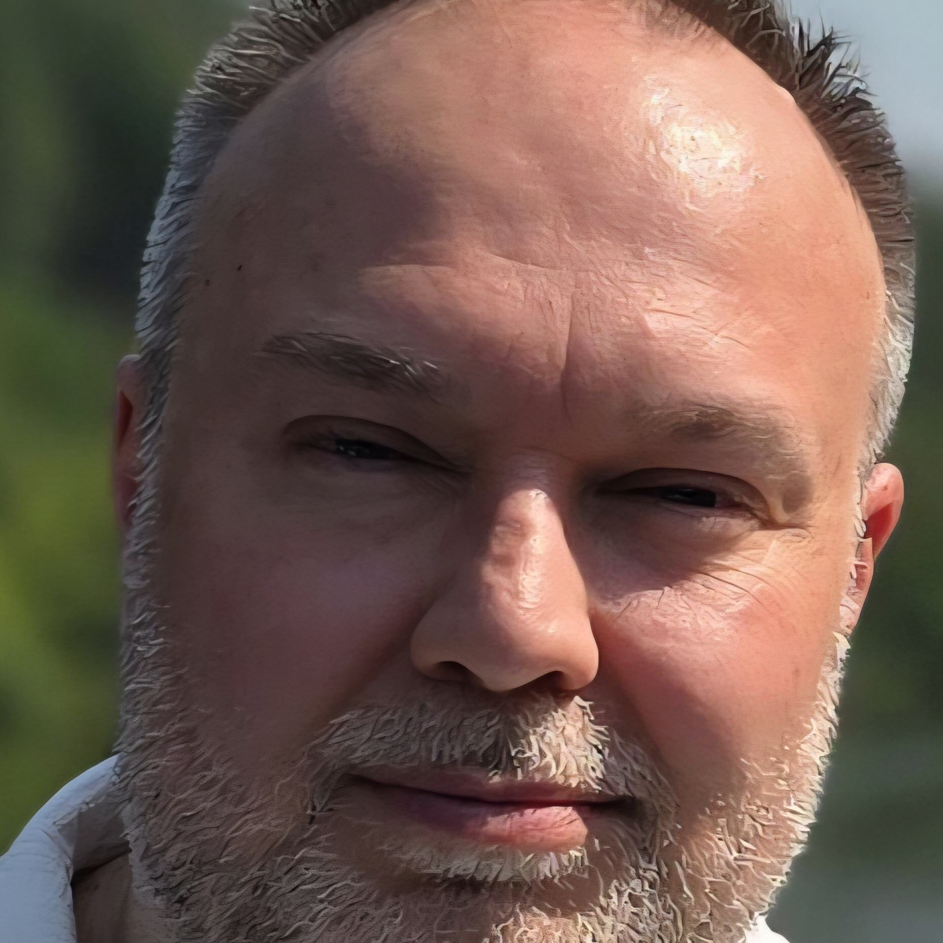 Portraitaufnahme einer Person mit kurzen Haaren, Bart und hellem Hemd.