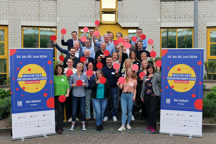 Gruppenbild mit rund 30 Personen mit roten Punkten in der Hand, Roll-ups zur Woche der Medienkompetenz