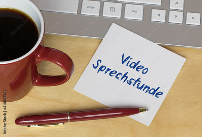 Kaffeetasse, Kugelschreiber und ein mit "Video-Sprechstunde" beschrifteter Zettel vor einer Tastatur