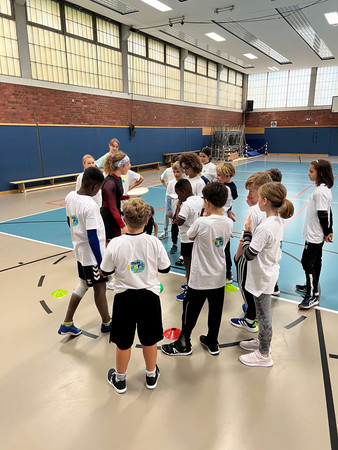 Schüler/innen in der Sporthalle bei einer Besprechung