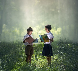 Kinder stehen im Wald und lesen.
