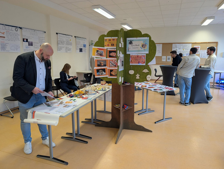 Ausstellungsraum des Studienseminar BBS Neuwied mit Informationen zur Ausbildung von Lehrkräften. Im Raum befinden sich Personen, die sich die Informationen auf Plakaten anschauen und Personen, die miteinander reden.