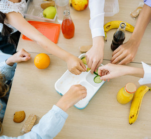 Kinder essen zusammen am Tisch Obst