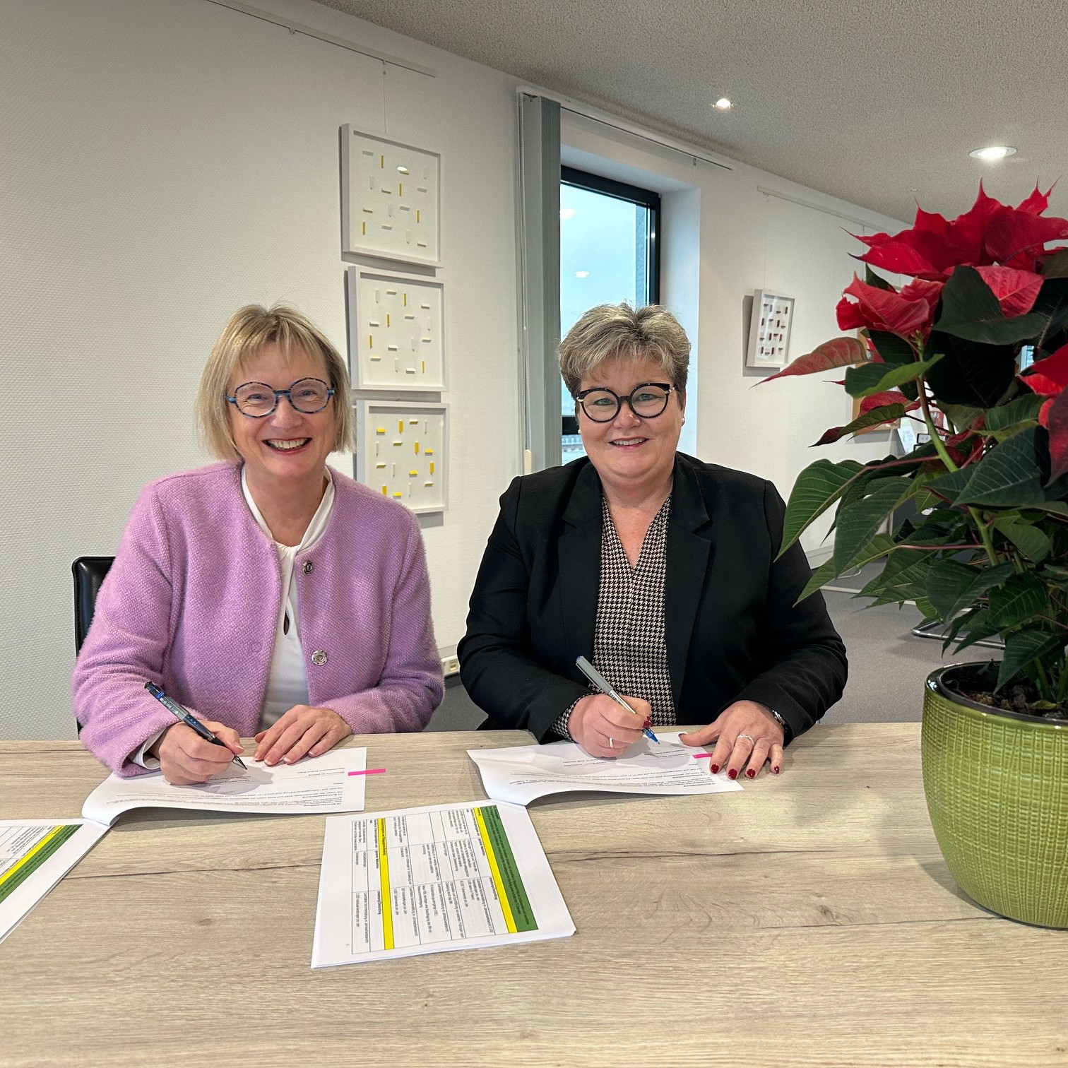 Bildungsstaatssekretärin Bettina Brück und Direktorin Dr. Birgit Pikowsky sitzen hinter einem Tisch und unterzeichnen die Zielvereinbarung 