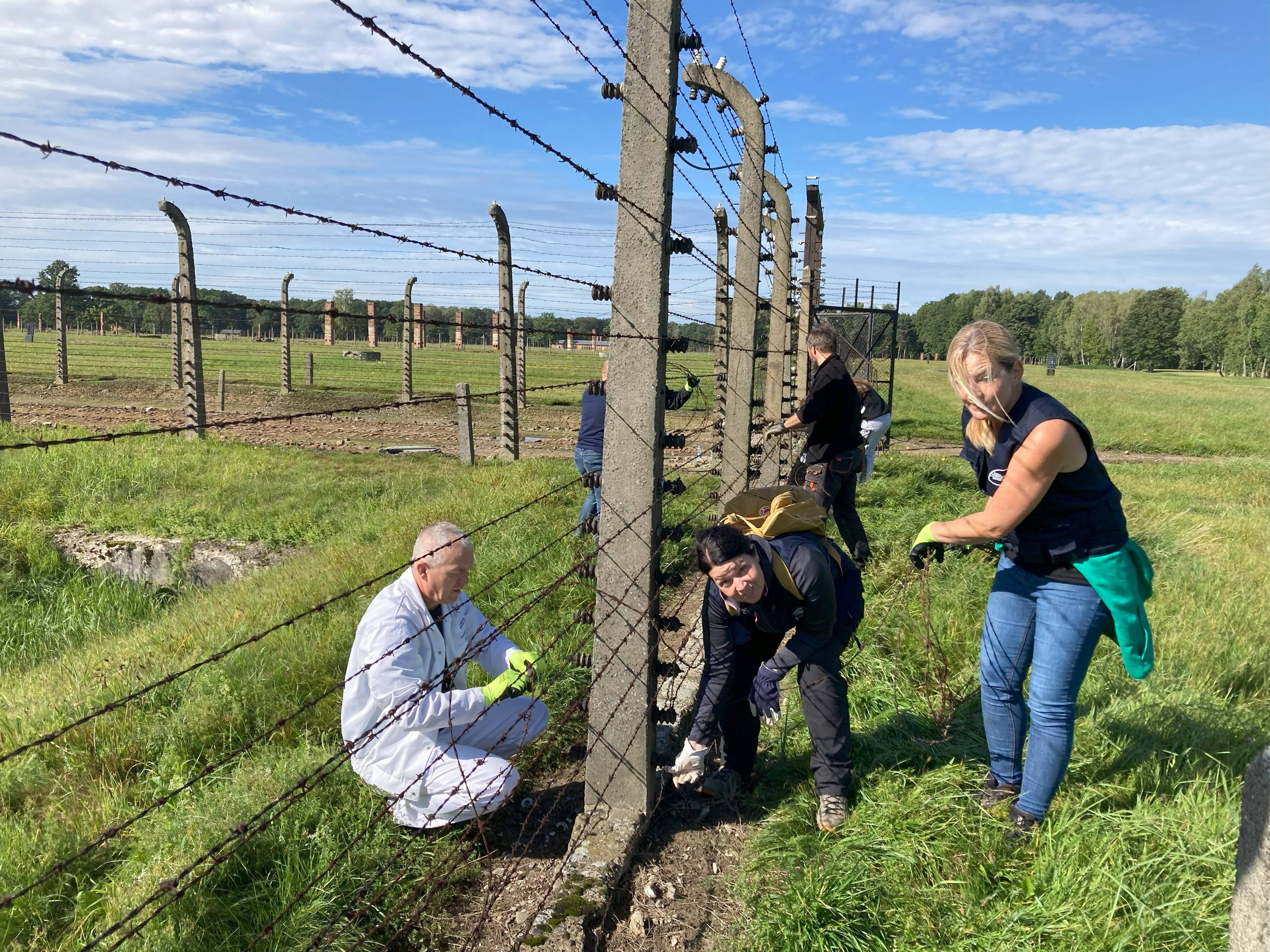 Reparatur- und Instandsetzungsarbeiten am Zaun des Lagers der Gedenkstätte in Auschwitz durch eine Fachleiterin, eine Anwärterin und einen polnischen Ausbilder von VW