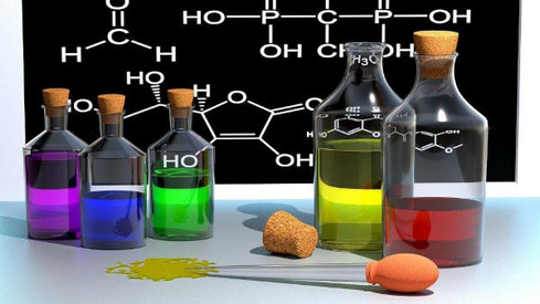 Chemikalien in Behältnissen vor Kreidetafel mit Formeln