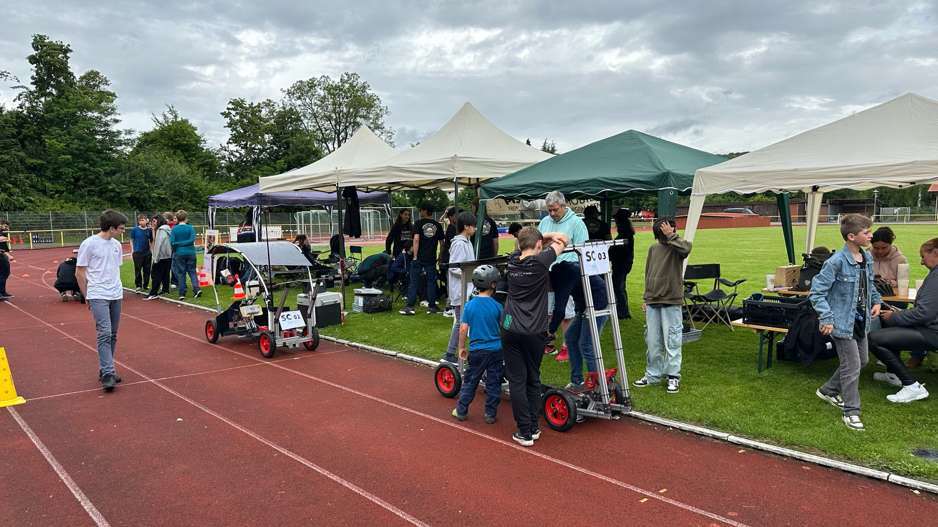 Das Bild zeigt die Boxengasse mit Pavillons für die Teams und Elektro-Cars davor.