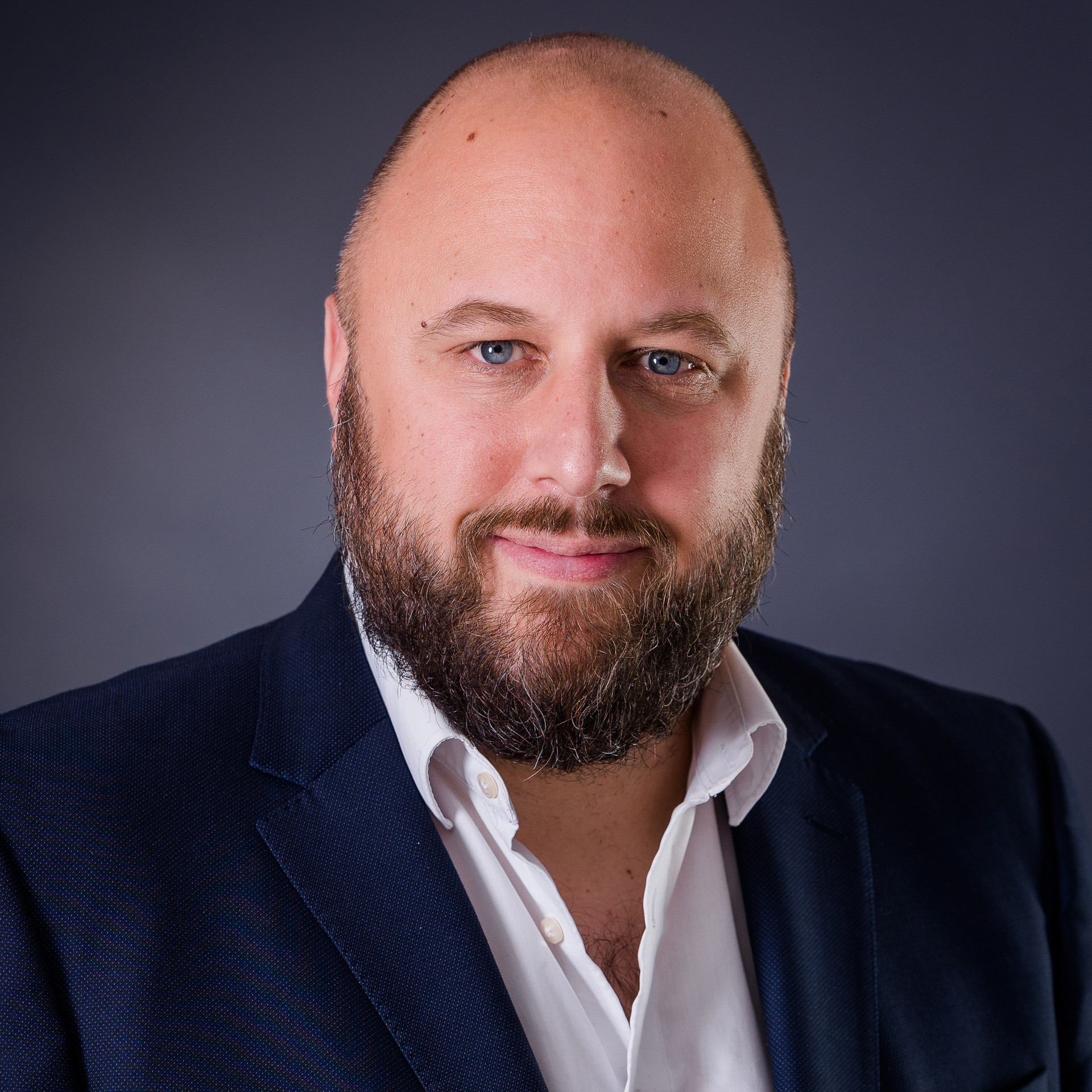 Portraitaufnahme einer Person mit Bart, dunklem Jackett und weißem Hemd