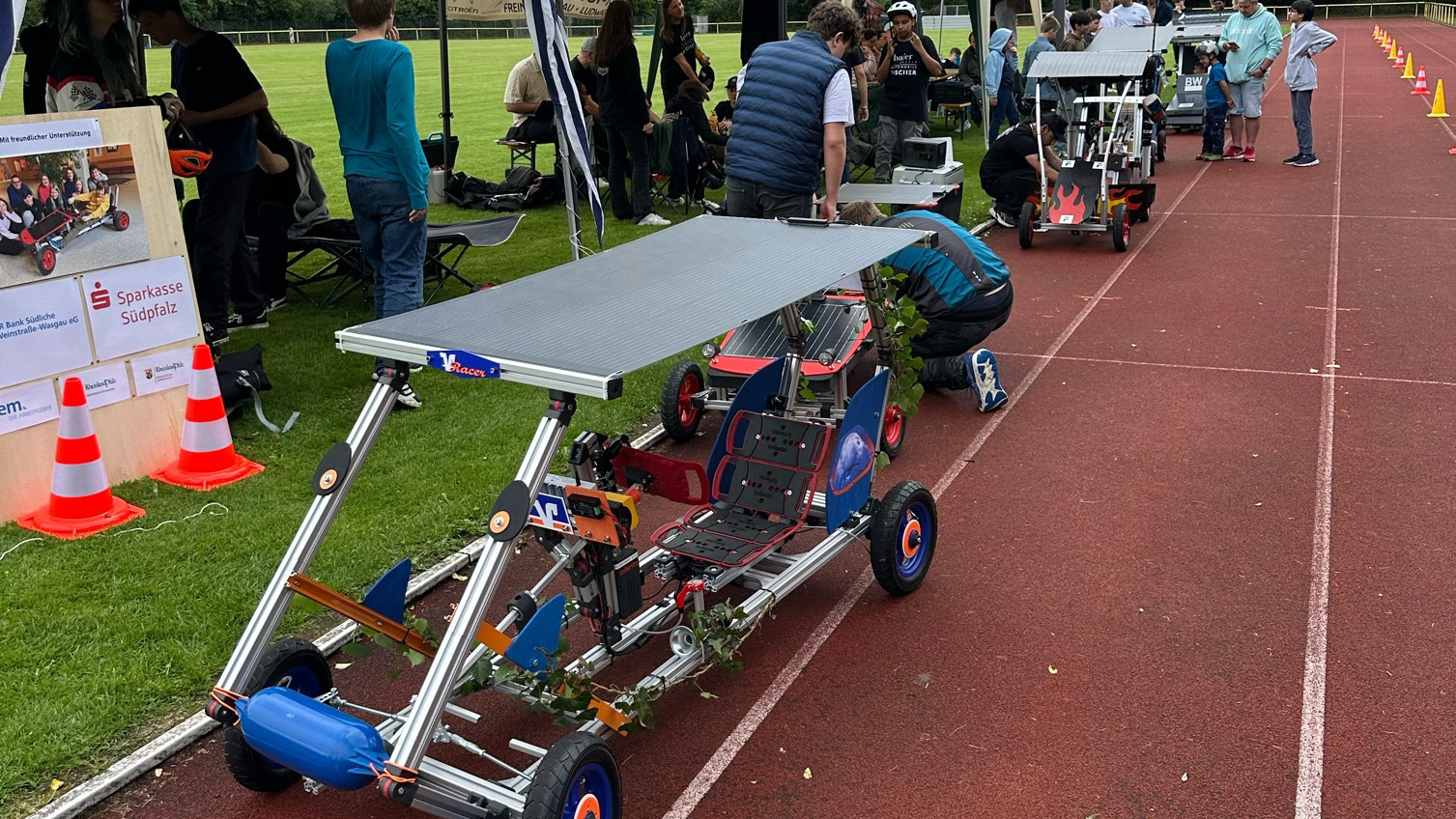 Das Bild zeigt die Boxengasse mit Pavillons für die Teams und Elektro-Cars davor.