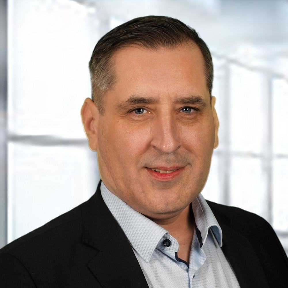 Portraitfoto einer Person mit kurzen Haaren, dunklem Jackett und hellem Hemd