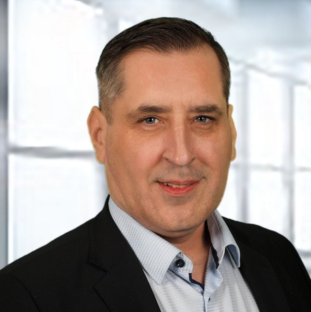 Portraitfoto einer Person mit kurzen Haaren, dunklem Jackett und hellem Hemd