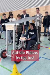 Das Bild zeigt Bildungsminister Sven Teuber in einem SolarCar der Realschule plus Germersheim sitzen. 