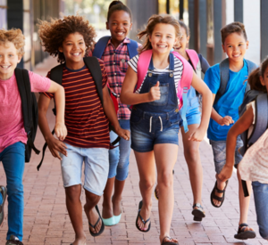 Fröhliche Schulkinder rennen auf den Schulhof.