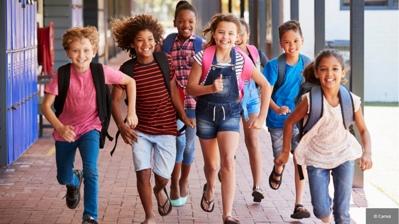 Fröhliche Schulkinder rennen auf den Schulhof.
