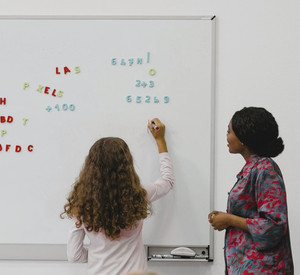 Lehrerin und Schülerin an einer Magnetwand mit Buchstaben