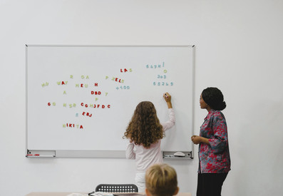 Lehrerin und Schülerin an einer Magnetwand mit Buchstaben