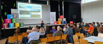 Illustration: Foto der mit Teilnehmenden gut gefüllten Aula der Alfred-Delp-Schule in Hargesheim