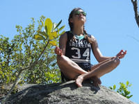 Mädchen beim Yoga auf einem Felsen sitzend