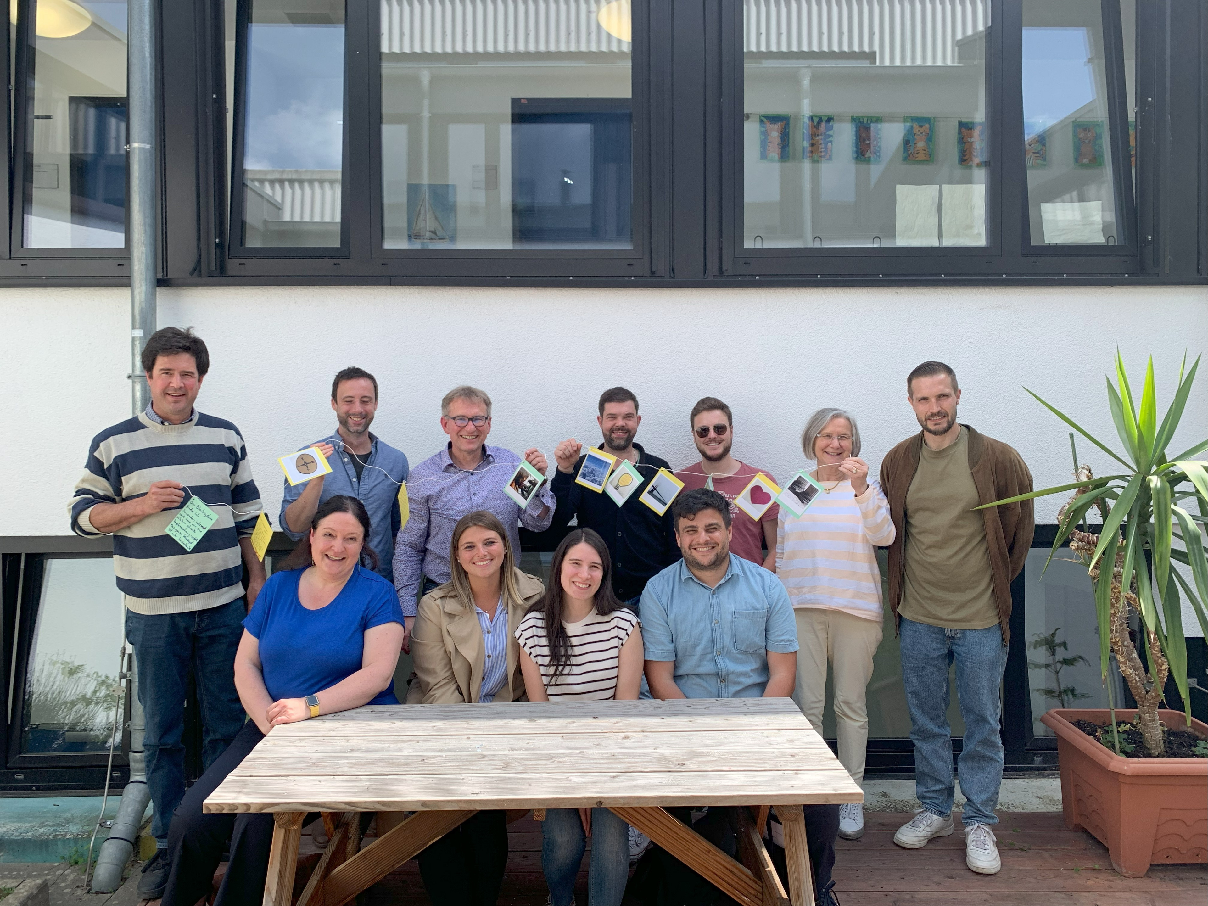 Gruppenfoto mit unserem Geschenk - Gemeinsames Gruppenfoto auf dem unser Abschlussgeschenk zu sehen ist.  Das Geschenk ist im Anschluss an der Schulführung entstanden. Jeder Besucher hat sich ein emotionales Foto ausgesucht und auf der Rückseite eine Botschaft hinterlassen.