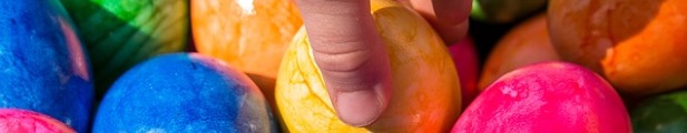Illustration: eine Hand greift ein Osterei aus einer Menge bunter Ostereier heraus