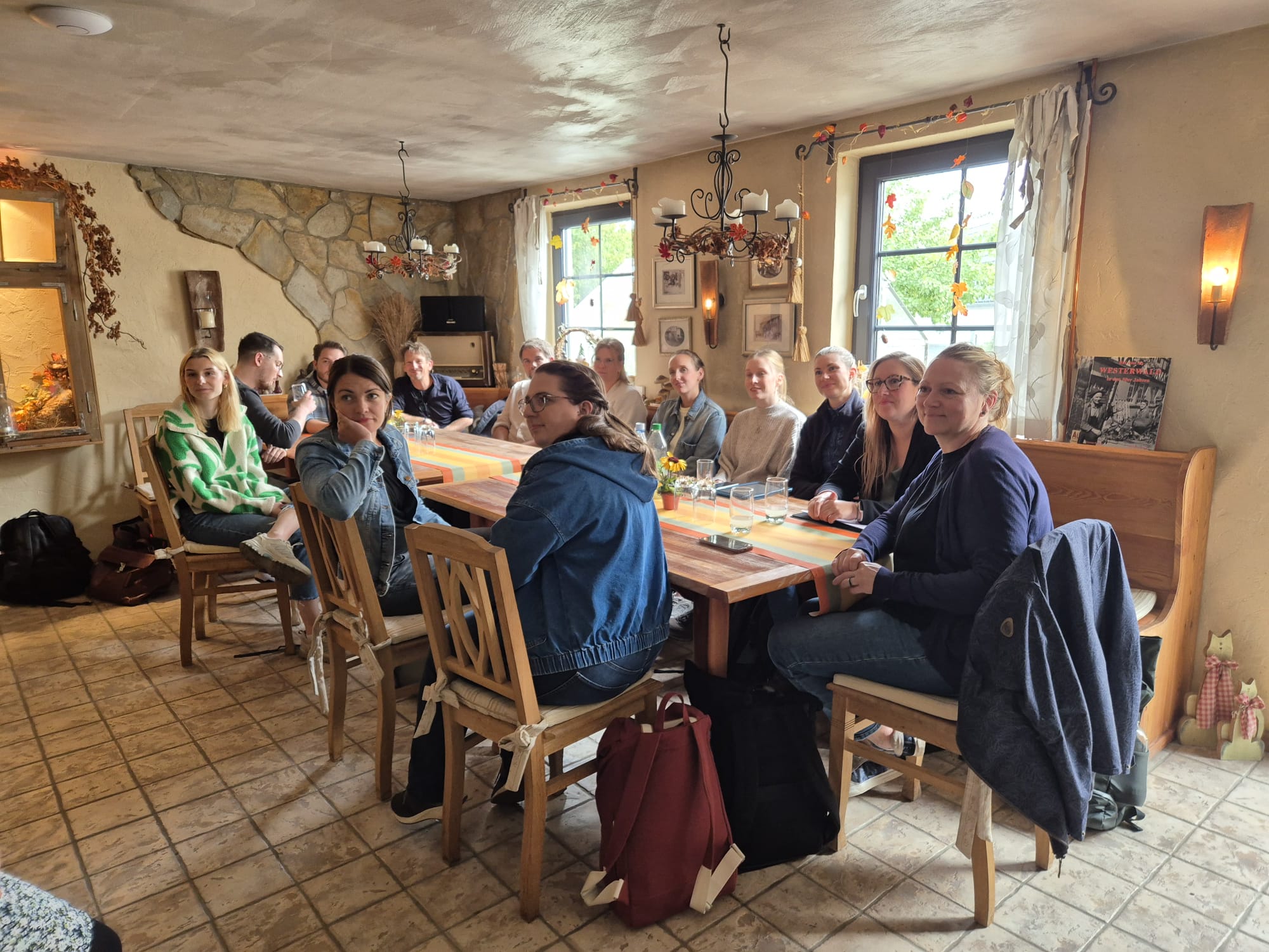 Nach dem Rundgang findet ein Austausch über die gemachten Erfahrungen im Tagesraum statt. Hier konnten auch Fragen an die Hausleitung gestellt werden. Das Foto zeigt einen gemütlichen Raum mit einem großen Tisch, an dem die Teilnehmerinnen und Teilnehmer sitzen.