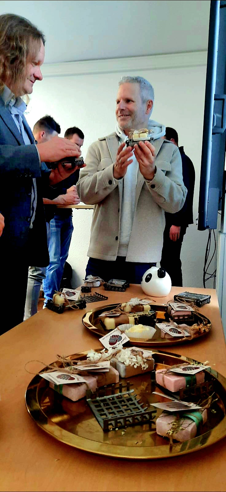 Das Bild zeigt die Pflegeprodukte, die im Rahmen des Projekts "Hand in Hand - Pflegeprodukte für alle" entwickelt wurden. Sie werden von Zuschauern begeistert betrachtet.